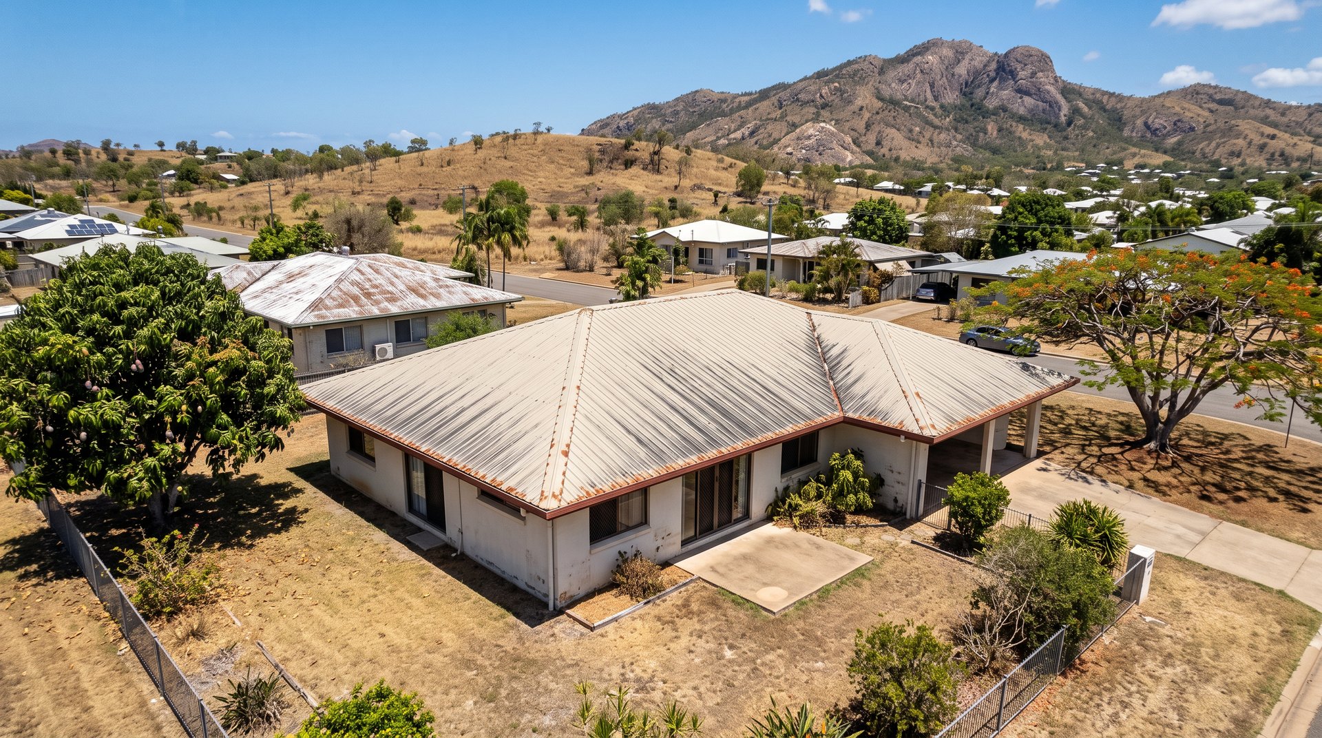 Before: Townsville home with a faded, rust-streaked Colorbond roof, Castle Hill in the background